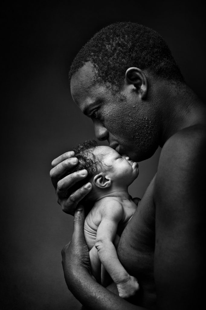 Dad is holding his precious daughter in a black and white fine art portraits